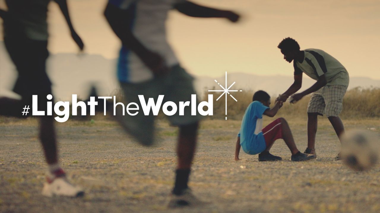 Un garçon aide un camarade à se lever après sa chute en jouant au football, tirée de la vidéo « Éclairer le monde »