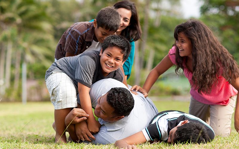 Une famille qui joue au football dans un parc se conforme à la Parole de Sagesse