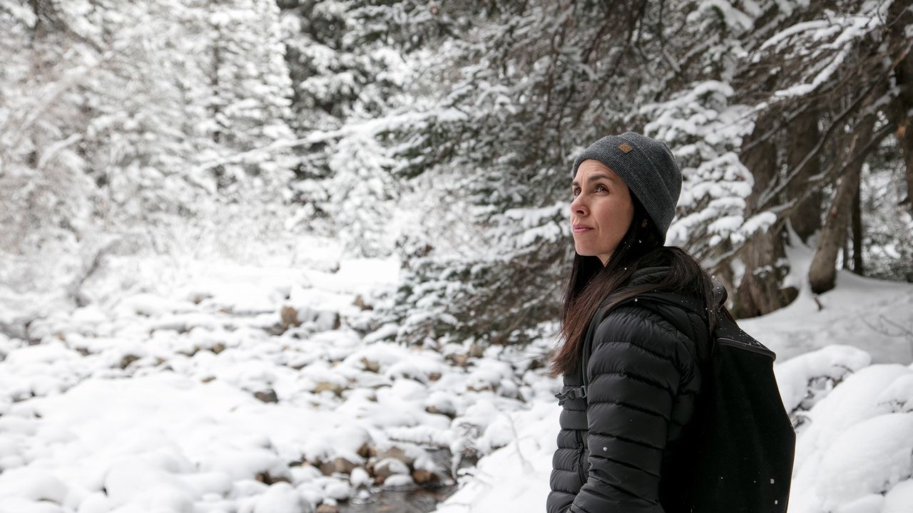 Une femme dans une forêt sous la neige tombante réfléchit à la place de Dieu dans sa vie