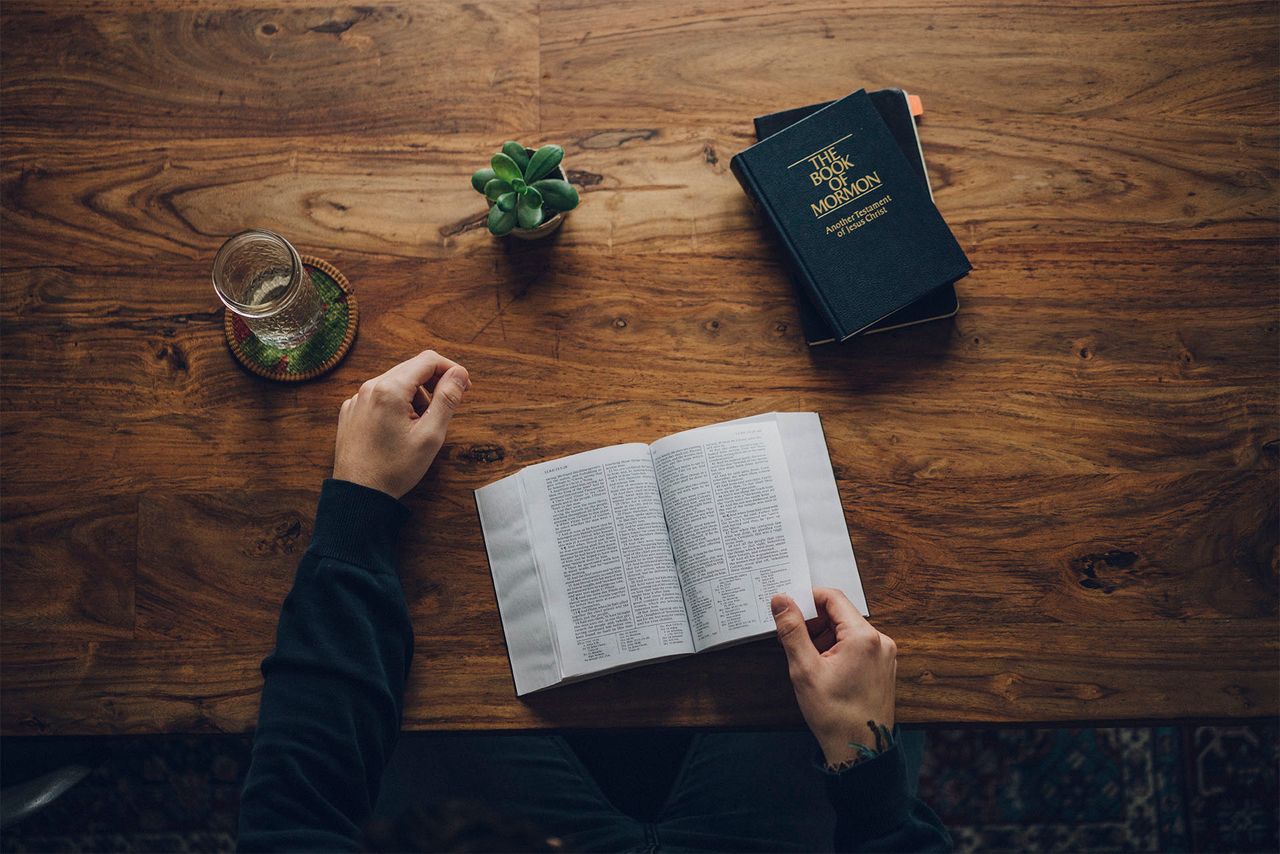 Un homme, assis à sa table de cuisine, étudie la Bible et le Livre de Mormon