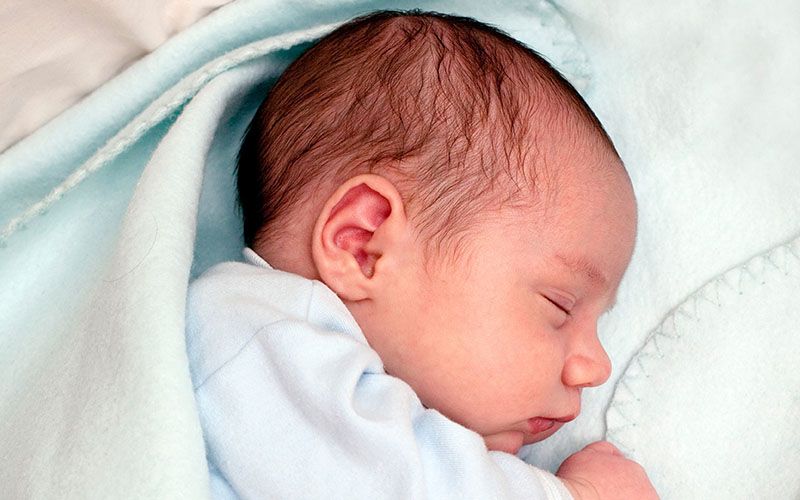 Un nouveau-né endormi, enveloppé dans une couverture